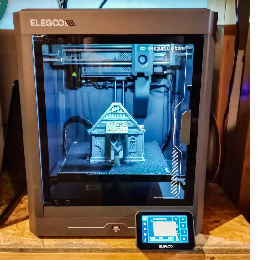 An ELEGOO Centauri Carbon 3-D printer partway through printing a model house